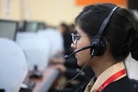 Side view of a woman working in a call center, wearing a headset and focused on her task.