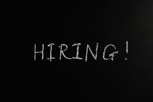 Close-up of the word 'Hiring!' written in white chalk on a blackboard, ideal for recruitment themes.