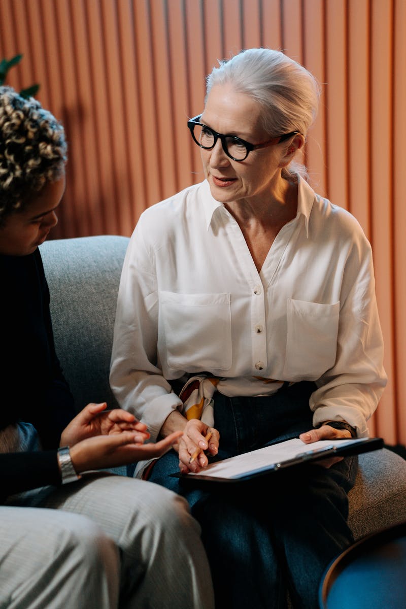 Two professional women engaged in a business discussion indoors with documents.